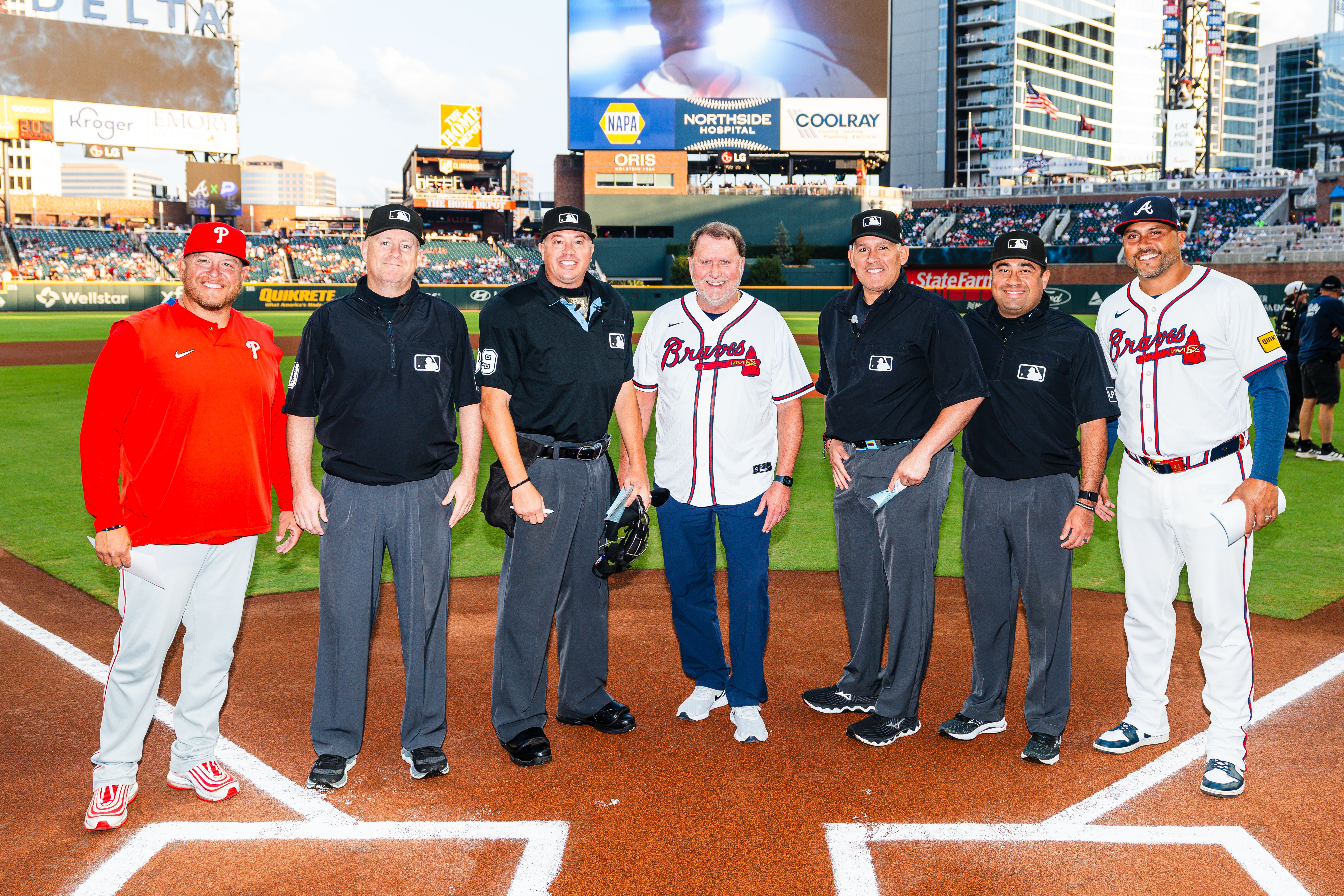 Larry in a Braves uniform with Braves players on the ball field. 