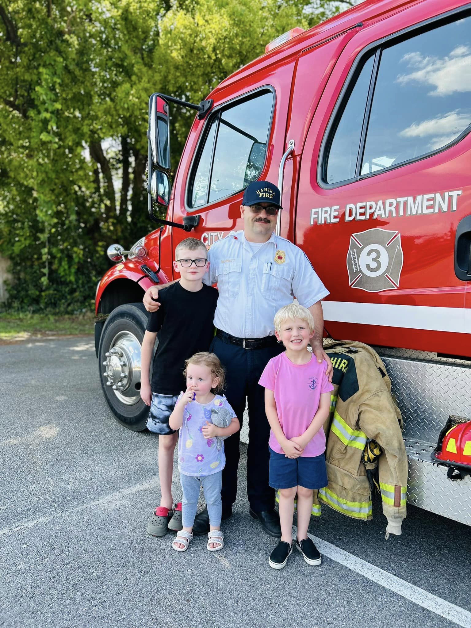 Fire Chief with local kids next to fire truck. 